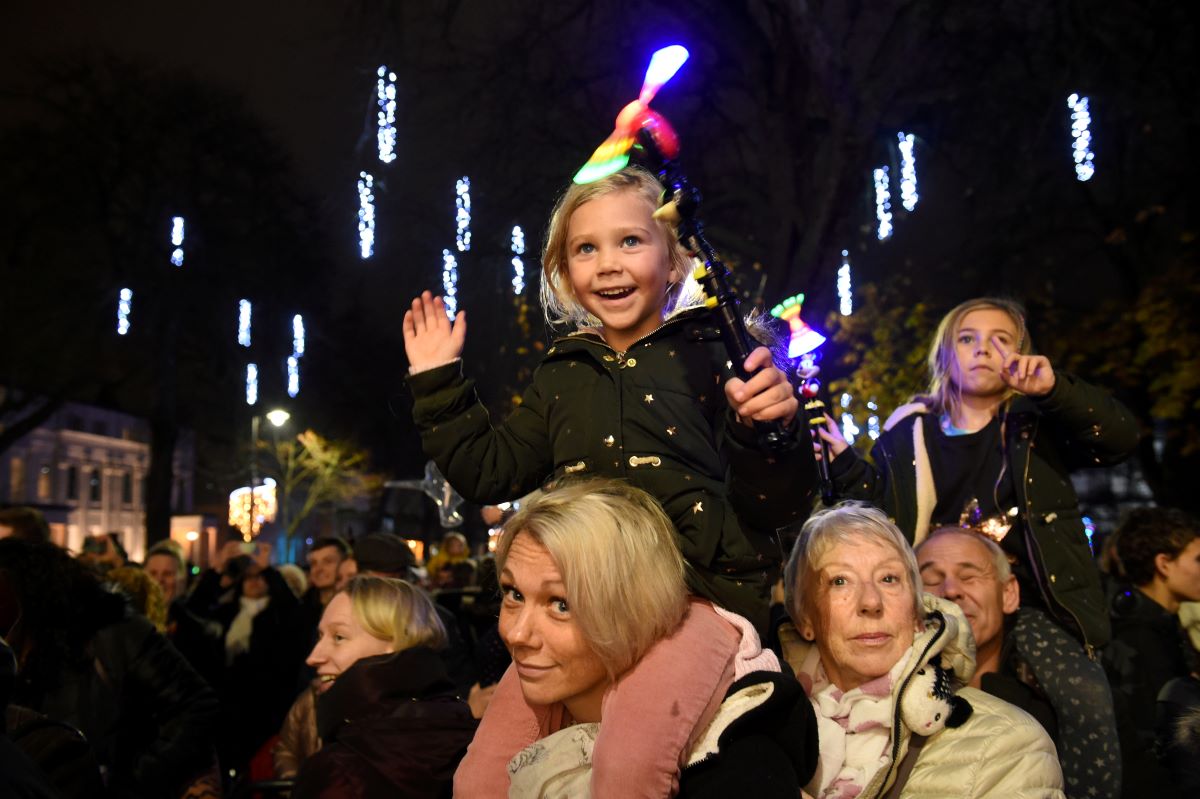 Child on mother's shoulders enjoying Christmas Light Switch On